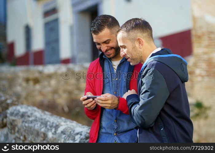 Gay couple looking at their smartphone. LGTB relationship concept.. Gay couple looking at their smartphone outdoors