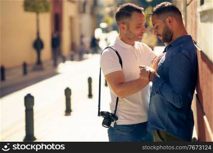 Gay couple tourists in a romantic moment on the street. Homosexual relationship concept.. Gay couple in a romantic moment outdoors