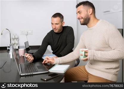 Gay couple working together at home with their laptops. Lifestyle concept.. Gay couple working together at home with their laptops.
