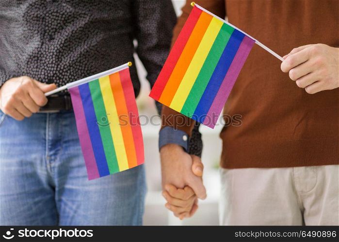 gay pride, lgbt and homosexual concept - close up of happy male couple with rainbow flags holding hands. male couple with gay pride flags holding hands. male couple with gay pride flags holding hands