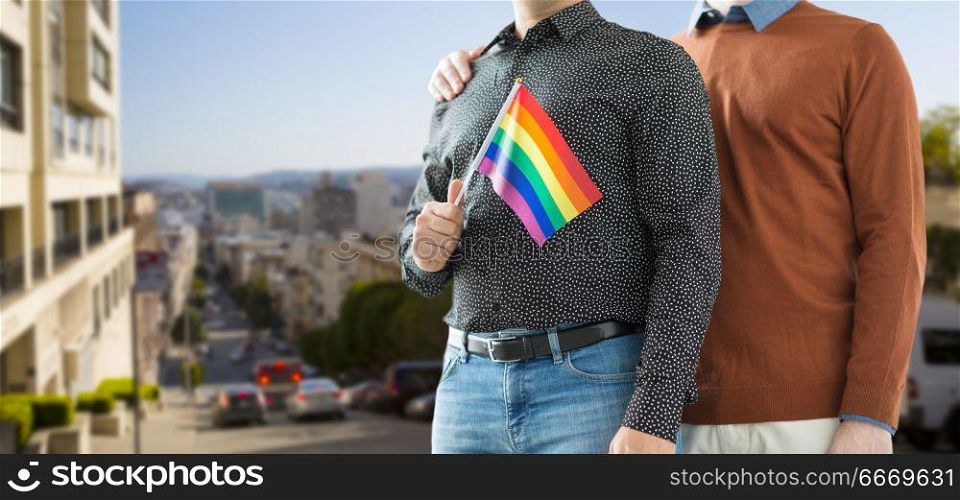 gay pride, lgbt and homosexual concept - close up of happy male couple with rainbow flags over san francisco city background. close up of happy male couple with gay pride flags. close up of happy male couple with gay pride flags