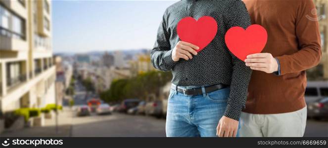 gay pride, lgbt and homosexual concept - close up of happy male couple holding red hearts over san francisco city background. close up of happy male couple holding red hearts. close up of happy male couple holding red hearts