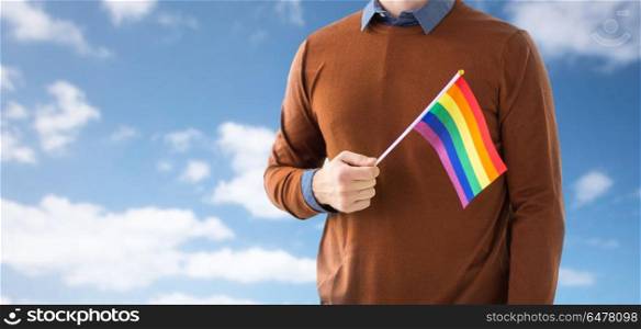 gay pride, lgbt and homosexual concept - close up of man with rainbow flag over blue sky and clouds background. close up of man with gay pride rainbow flag. close up of man with gay pride rainbow flag