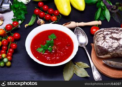 Gazpacho spanish cold soup in a white round ceramic plate on a black background