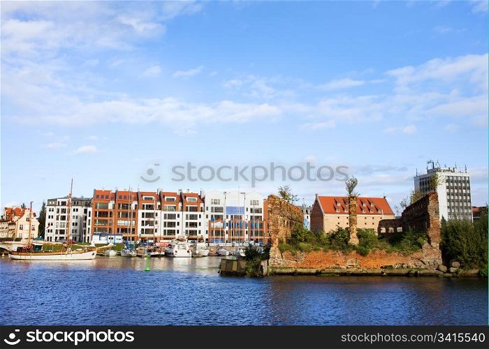 Gdansk cityscape in Poland at the Motlawa river, on the left modern apartment houses and marina on the right ruins of the old granary