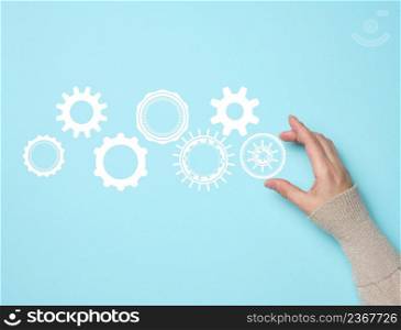 gear wheels and female hand on a blue background. Business structure precise work concept, team unification