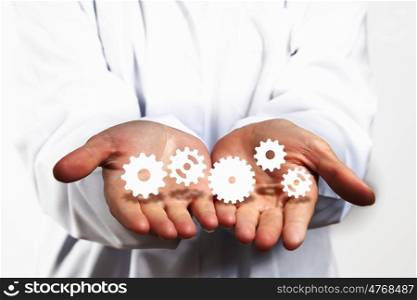 Gears in hands. Close up of human hands holding white gers