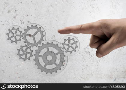 Gears mechanism. Close up human hand pointing with finger at gears mechanism