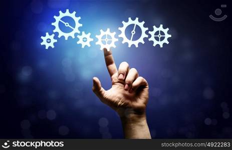 Gears mechanism. Close up human hand pointing with finger at gears mechanism