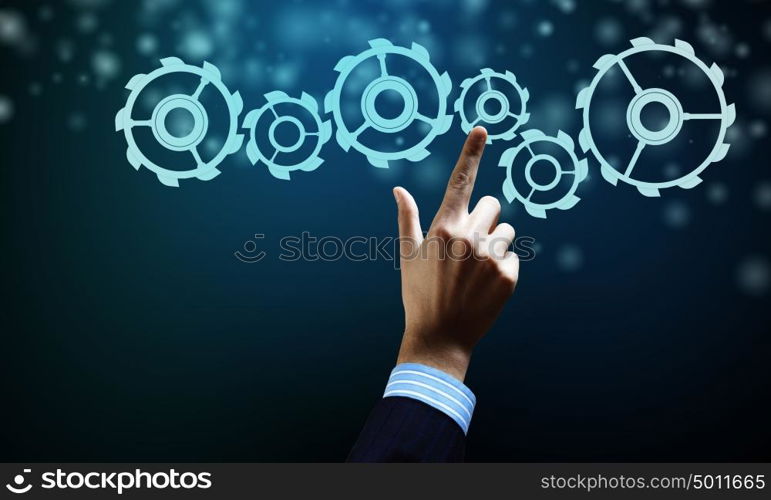 Gears mechanism. Close up human hand pointing with finger at gears mechanism