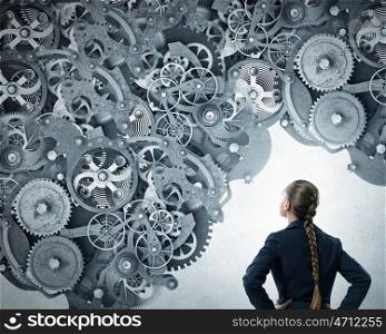 Gears working mechanism. Young businesswoman standing with back and looking at gears mechanism