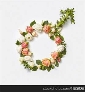 Gender symbol sign of man handmade from flowers and green branch of plant on a light grey background, copy space. Top view.. Male sign made from flowers.