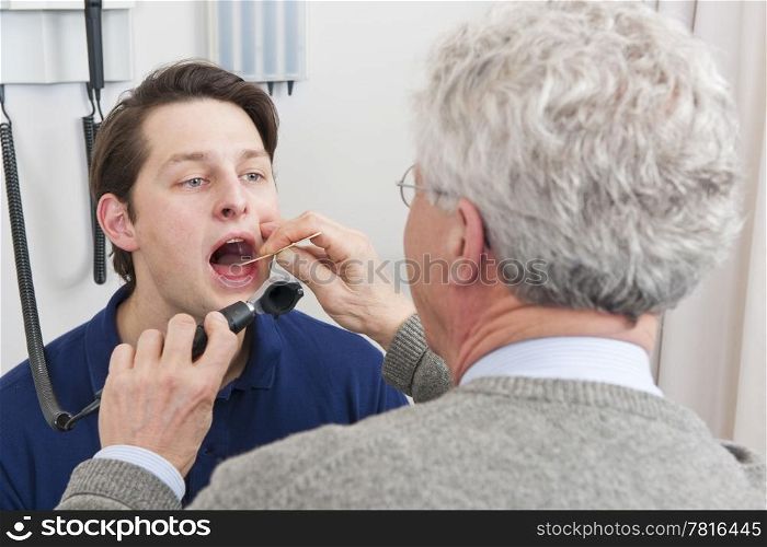 General practitioner examining mouth and throat of a patient with laryngitis