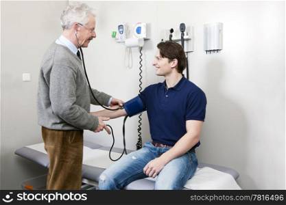 General practitioner taking the blood pressure off a young patient
