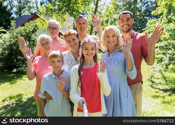generation and people concept - happy family taking picture with selfie stick in summer garden. happy family taking selfie in summer garden