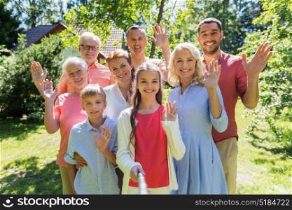 generation and people concept - happy family taking picture with selfie stick in summer garden. happy family taking selfie in summer garden