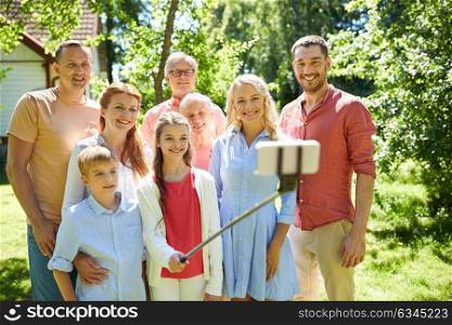 generation and people concept - happy family taking picture with smartphone and selfie stick in summer garden. happy family taking selfie in summer garden