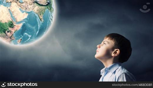 Generation next. Little boy of school age looking at Earth planet. Elements of this image are furnished by NASA