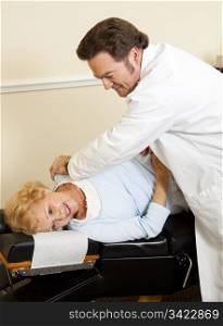Gentle chiropractor adjusting happy senior patient in his office.