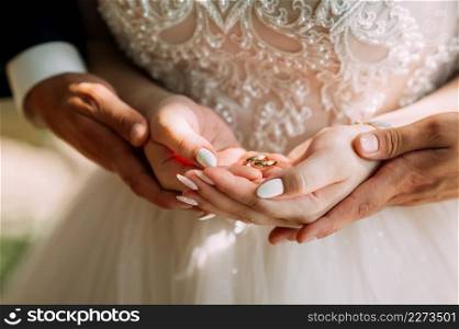 Gentle embrace of the hands of the newlyweds.. Sunny photo of the newlyweds holding hands 3910.