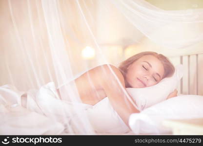 Gentle female sleeping in the bedroom under canopy, with pleasure relaxing in luxury spa resort, enjoying, calmness and harmony
