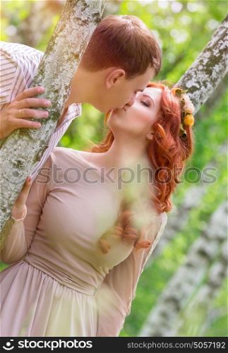 Gentle young happy couple kissing in the park, standing between two beautiful birch tree, celebrate wedding day, love and togetherness concept