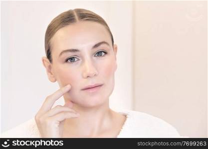 Genuine beauty of a young woman with natural makeup, applying anti aging cream, nice female with perfect clear facial skin, beauty and health care concept