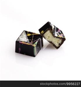 geometric shaped luxury chocolate handmade candy bonbons stuffed with coconut ganache decorated with colorful abstract art on white background