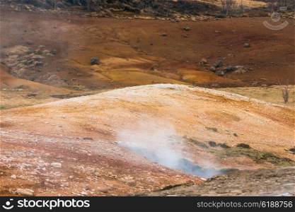 Geothermal activity in icelandic nature with steam coming up from the ground
