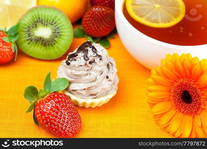 gerbera,lemon tea,mandarin,kiwi,cake and strawberries lying on the orange fabric