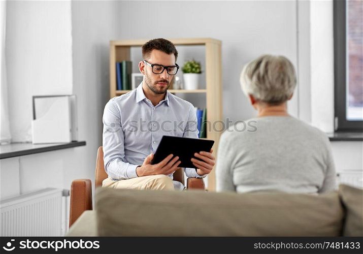 geriatric psychology, mental therapy and old age concept - psychologist with tablet computer and senior woman patient at psychotherapy session. psychologist with tablet pc and senior patient