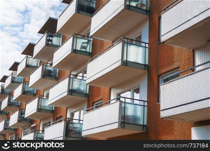 German apartment building with white balconies and orange brick walls against the sky, on a sunny day, in Sylt, Germany.