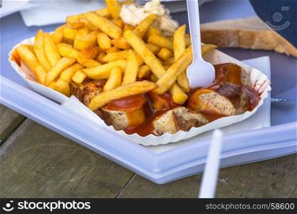 German currywurst served in a dish with golden fries and mayonnaise.
