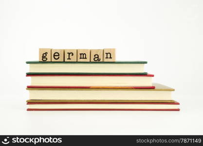 german word on wood stamps stack on books, foreign language and translation concept
