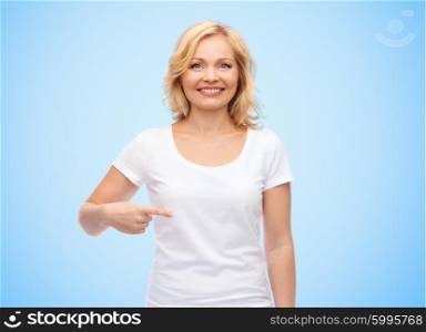 gesture, advertisement and people concept - smiling middle aged woman in blank white t-shirt pointing finger to herself over blue background