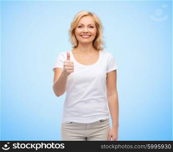 gesture, advertisement and people concept - smiling middle aged woman in blank white t-shirt showing thumbs up over blue background