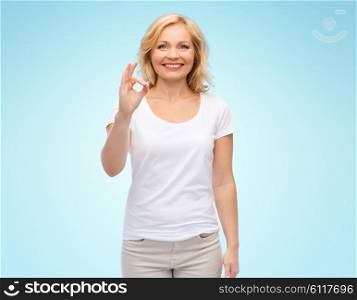 gesture, advertisement and people concept - smiling woman in blank white t-shirt showing ok hand sign over blue background
