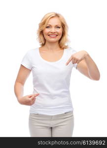 gesture, advertisement and people concept - smiling woman in blank white t-shirt pointing finger to herself