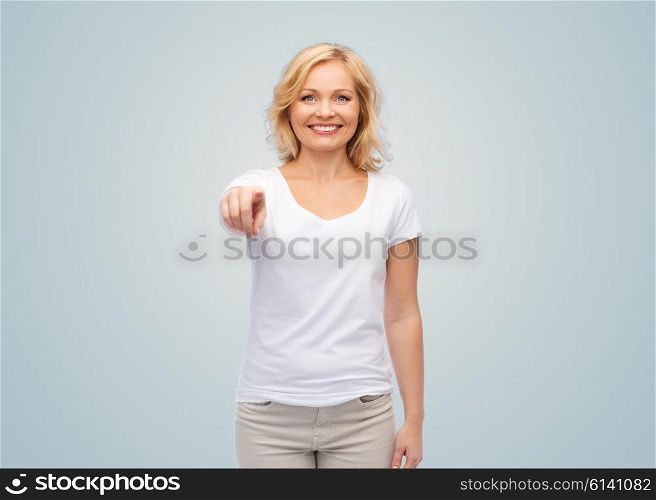 gesture, advertisement and people concept - smiling woman in blank white t-shirt pointing finger to you over gray background