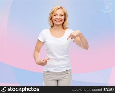 gesture, advertisement and people concept - smiling woman in blank white t-shirt pointing finger to herself over pink and violet background
