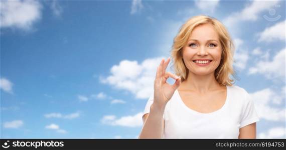 gesture, advertisement and people concept - smiling woman in blank white t-shirt showing ok hand sign over blue sky and clouds background