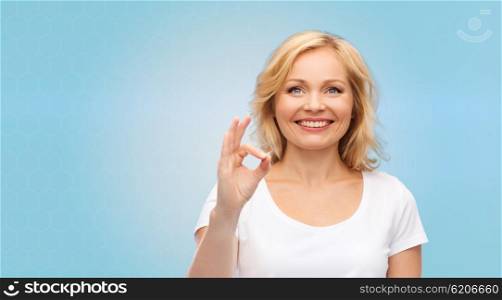 gesture, advertisement and people concept - smiling woman in blank white t-shirt showing ok hand sign over blue background