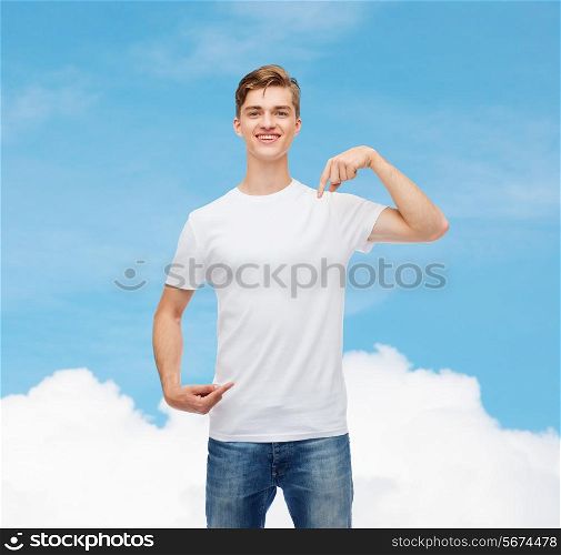 gesture, advertising, dream and people concept - smiling young man in blank white t-shirt pointing fingers on himself over blue sky background