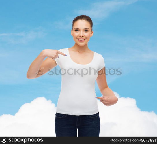 gesture, advertising, dream and people concept - smiling young woman in blank white t-shirt pointing fingers on herself over blue sky background