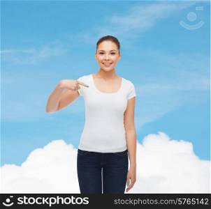 gesture, advertising, dream and people concept - smiling young woman in blank white t-shirt pointing finger on herself over blue sky background