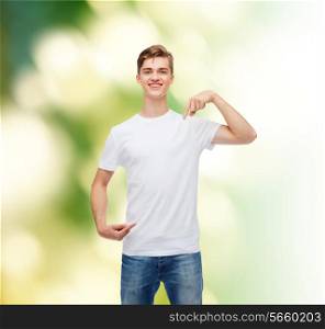 gesture, advertising, ecology and people concept - smiling young man in blank white t-shirt pointing fingers on himself over green background