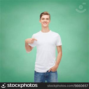 gesture, advertising, education, school and people concept - smiling young man in blank white t-shirt pointing finger on himself over green board background