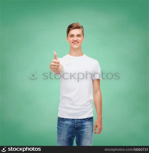 gesture, advertising, education, school and people concept - smiling young man in blank white t-shirt showing thumbs up over green board background