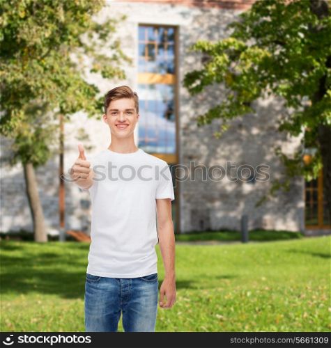 gesture, advertising, summer vacation, education and people concept - smiling young man in blank white t-shirt showing thumbs up over campus background