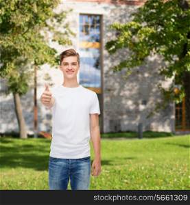gesture, advertising, summer vacation, education and people concept - smiling young man in blank white t-shirt showing thumbs up over campus background